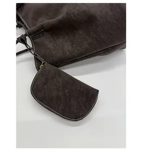Close-up of dark brown suede tote bag with contrast stitching and matching coin purse