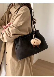 Deep grey suede tote bag featuring contrast stitching and a cute plush doll pendant