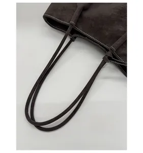 Detail of dark brown matte tote bag with contrast stitching and slim shoulder straps