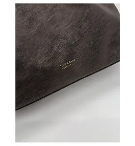 Detailed macro view of matte litchi grain leather and gold stamped logo on tote bag