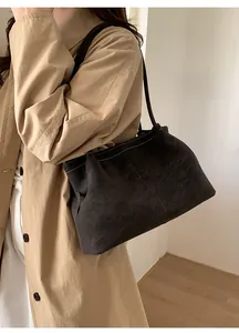 Detail of dark grey suede tote bag with white contrast stitching on khaki trench coat