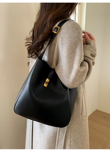 Outdoor shot of a vintage black leather tote bag with elegant gold twist-lock closure