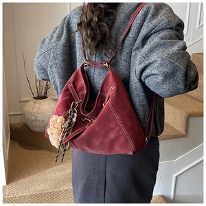 Deep red vintage tote bag with contrast stitching and teddy bear charm on model