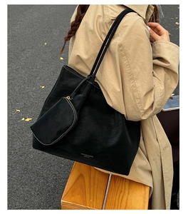 Detail of black leather tote bag featuring a small pouch and subtle gold logo branding