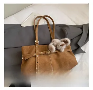 Detail view of brown suede tote bag with decorative buckle and plush rabbit charm