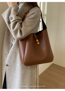 Detailed side view of a brown vintage leather bucket bag with a golden turn-lock closure