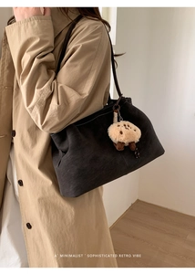 Detail view of large dark grey suede tote bag with plush charm and long shoulder straps