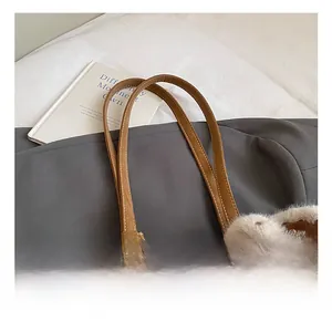 Detail of brown faux leather tote bag handle with a cute grey plush rabbit pendant