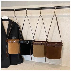 Minimalist suede bucket bags in brown, black, and khaki hanging from a metal rack