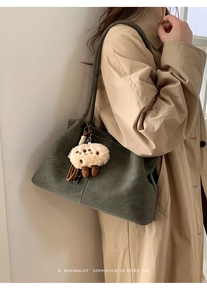 Minimalist olive suede tote bag with plush lamb pendant on khaki trench coat