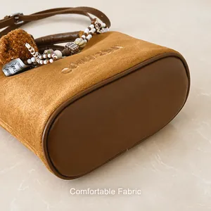 Detailaufnahme der braunen Wildleder-Beuteltasche mit Prägung und Anhänger