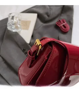 Close-up of bright red patent leather handbag with shiny gold buckle on silk background