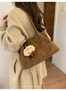 Brown suede tote bag with mushroom charm shown on shoulder over a beige coat