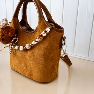 Nahaufnahme braune Wildleder-Tasche mit süßem Bärenanhänger und Perlendekoration