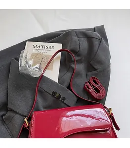 Detailed view of red patent leather shoulder bag on a grey blazer for a chic look