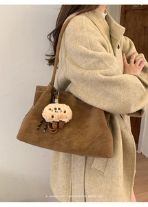 Brown suede tote bag with plush biscuit charm styled on beige wool coat outfit