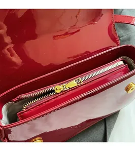 Detail of high-gloss red patent leather bag showing smooth gold metal zipper and hardware