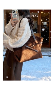 Dettaglio borsa tote in peluche marrone con tracolla in pelle in un ambiente innevato
