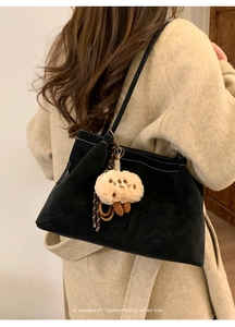 Minimalist black suede tote bag with white stitching and biscuit plush pendant detail