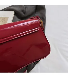 Detailed close-up of dark red patent leather bag with precise stitching and gold hardware
