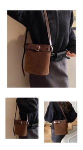 Détail du sac seau en daim marron avec boucle en cuir et tenue en tricot noir chic