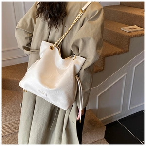 Close-up of cream leather tote bag with metal chain strap and drawstring details