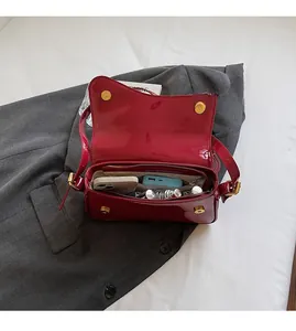Top view of red patent leather saddle bag interior showing gold clasp and roomy storage