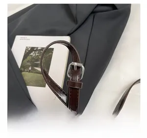 Gros plan sur la bandoulière réglable en cuir marron foncé avec boucle en argent