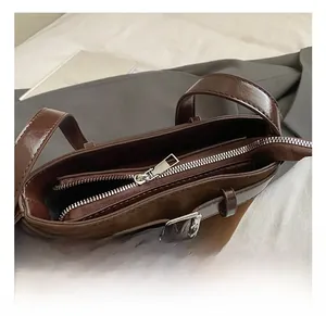 Close-up of brown suede bucket bag featuring silver zipper and leather buckle details