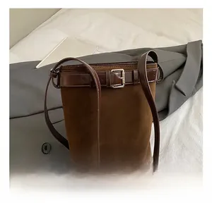 Detail showing brown suede bucket bag with leather belt buckle and silver metal clasp