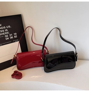 Detail of red and black patent leather shoulder bags with asymmetric cut and gold hardware