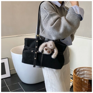Detail of black faux suede tote bag with white stitching and grey plush bunny charm
