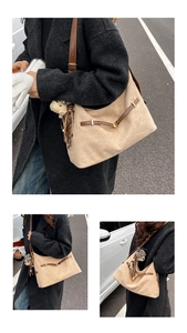 Detail of beige suede tote bag with brown leather straps and cute bear doll charm