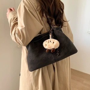 Detail of dark brown suede tote bag with white stitching and cute plush lamb pendant