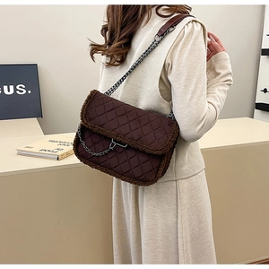 Close-up of quilted pattern and faux shearling trim on a dark brown shoulder bag