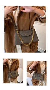 Detail of dark grey leather bag featuring bold gold chain strap and branding