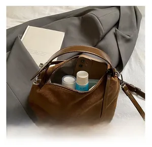 Détail de la grande capacité interne du sac à main en daim marron montrant des objets