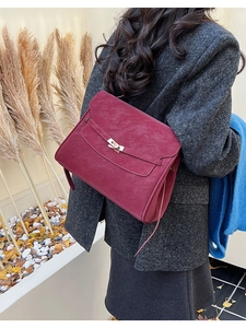 Detail of burgundy suede briefcase bag with gold twist lock on a wool coat outfit