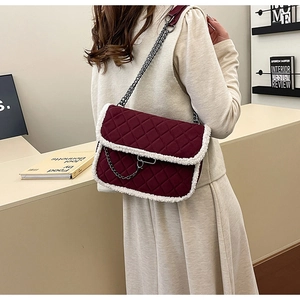 Detail of burgundy quilted bag with white shearling trim and silver chain on model