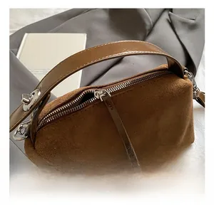 Gros plan d'un sac à main en daim marron avec boucles en argent et anse en cuir