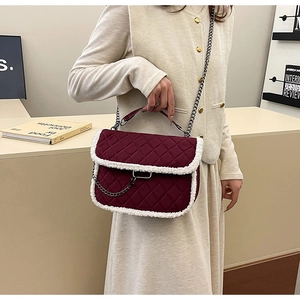 Detail of burgundy quilted chain bag with soft white faux fur trim and metal buckle