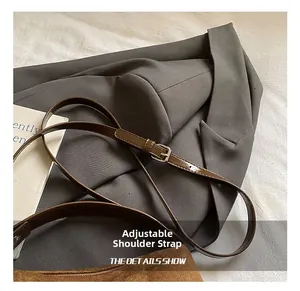 Détail de la bandoulière réglable en cuir avec boucle argentée sur un sac polochon en daim marron