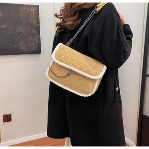 Detail of khaki quilted shoulder bag with white faux fur trim and metal chain strap