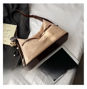Detail showing mixed beige suede and brown leather tote bag with bear charm