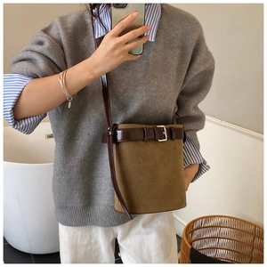 Vue détaillée du sac seau en daim marron avec boucle et fine bandoulière