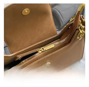 Détail de la fermeture éclair dorée et chaîne sur sac bandoulière vintage marron