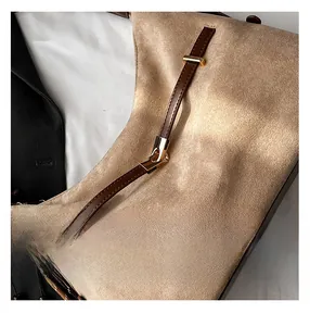 Detail of camel suede texture with dark brown leather straps and gold metal buckles