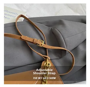 Détail de la bandoulière réglable en cuir marron avec boucle dorée et chaîne chic