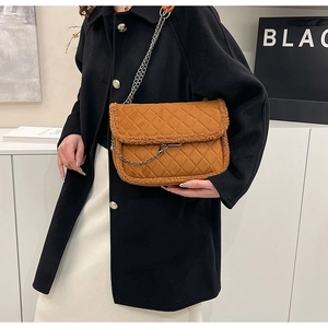 Close-up of caramel quilted bag with faux shearling trim and dark metal chain strap