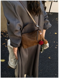 Detail of vintage brown suede shoulder bag with leather strap and decorative pompom charm